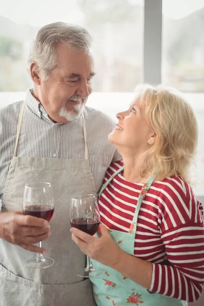 Coppia anziana che tiene bicchiere di vino in cucina — Foto Stock