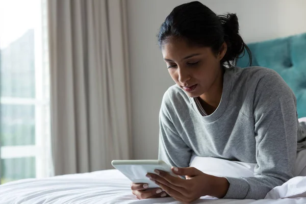 Mujer joven usando tableta en la cama — Foto de Stock