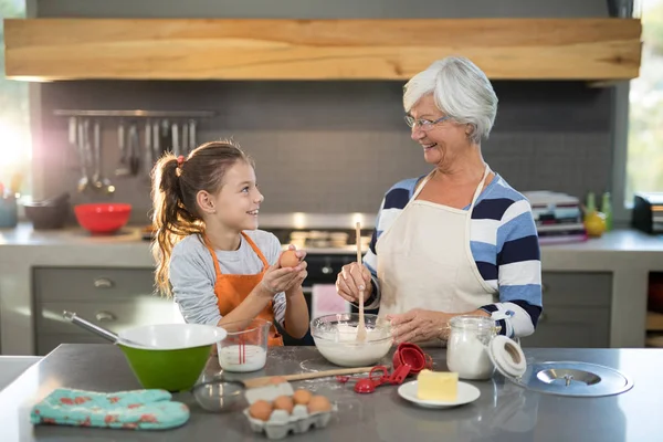 Granddaughter mixing flour in bowl with granddaughter — Stock Photo, Image