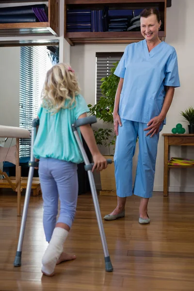Wspieranie pacjenta dziewczyny chodzić fizjoterapeuty — Zdjęcie stockowe
