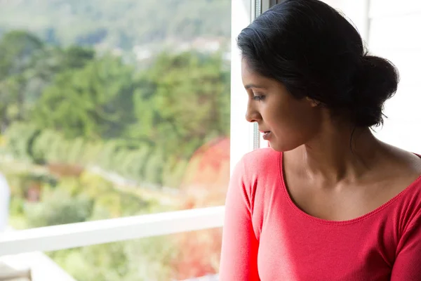 Eftertänksam kvinna som tittar genom fönstret — Stockfoto