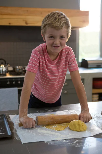 Усміхнений хлопчик котиться тісто — стокове фото