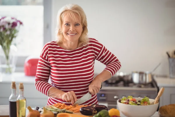 Senior vrouw hakken van groenten thuis — Stockfoto