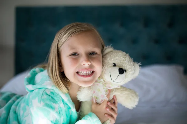 Meisje houdt van teddybeer op bed in de slaapkamer — Stockfoto