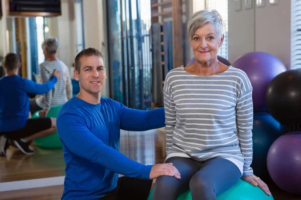 Pomoc starší ženě na cvičení míč fyzioterapeut — Stock fotografie
