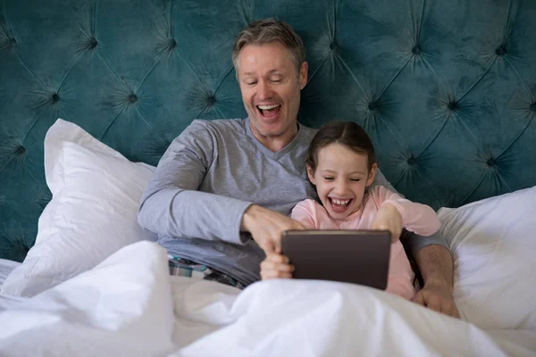 Father and daughter using tablet on bed — Stock Photo, Image
