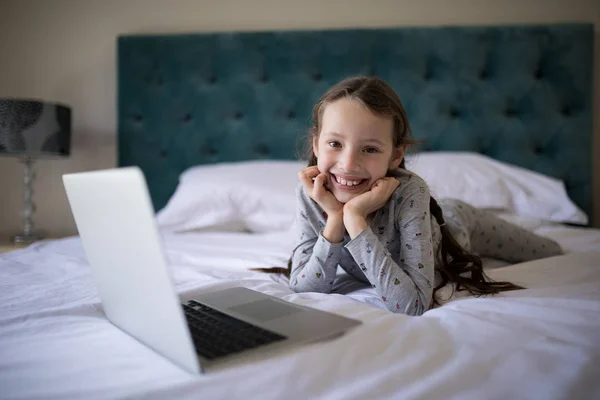 Menina deitada na cama com laptop no quarto — Fotografia de Stock