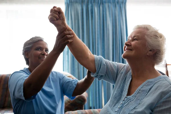 Nurse helping senior woman in flexing muscles — Stock Photo, Image