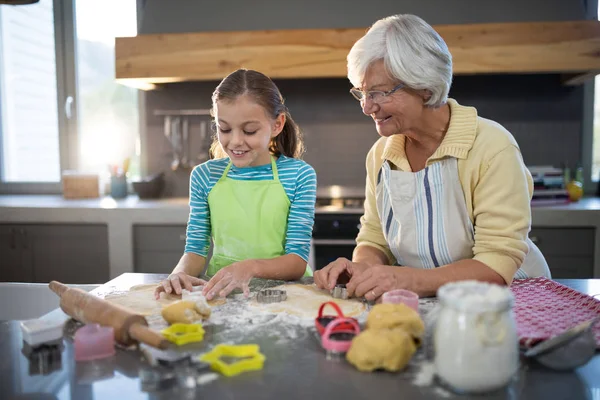 Grandmother and granddaughter cutting dough — Stock Photo, Image