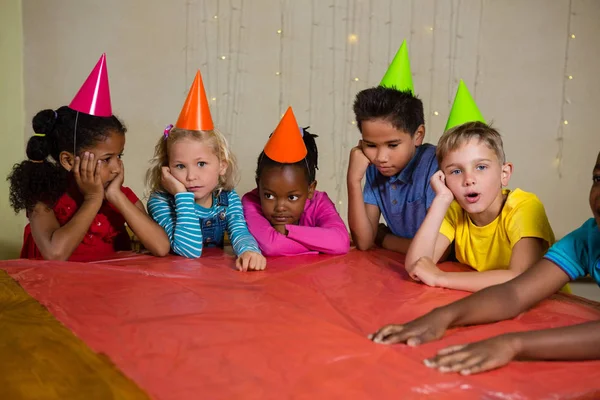 Набридли діти в частковому капелюсі за столом — стокове фото