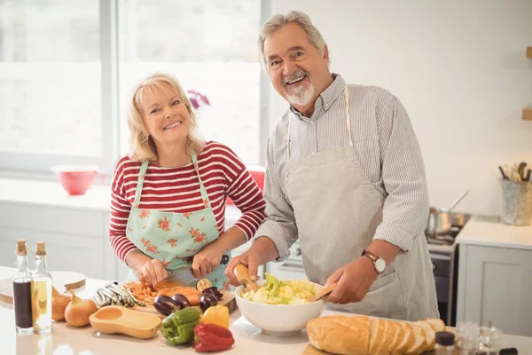 Starší pár připravuje salát v kuchyni — Stock fotografie