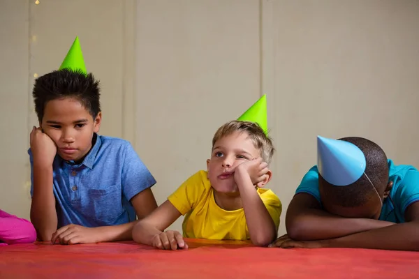 Enfants ennuyés portant un chapeau de fête à la table — Photo