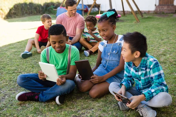 Kinderen met behulp van Tablet PC met man in het park — Stockfoto