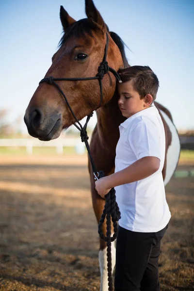 Rapaz cavaleiro acariciando um cavalo — Fotografia de Stock