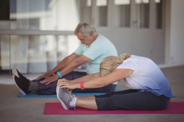 Casal sênior realizando exercício de alongamento — Fotografia de Stock