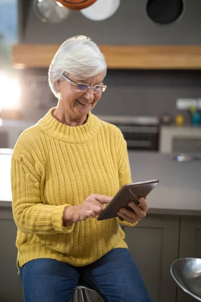 Mujer mayor usando tableta en la cocina — Foto de Stock