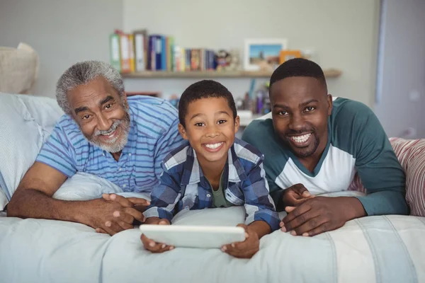 Familia multigeneración que utiliza tableta en la cama — Foto de Stock