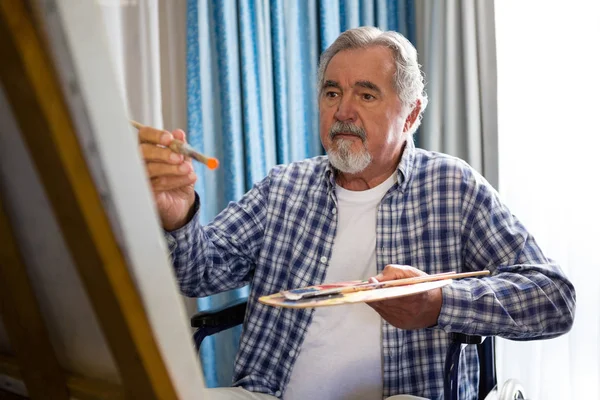 Senior homme peinture tandis que assis sur fauteuil roulant — Photo