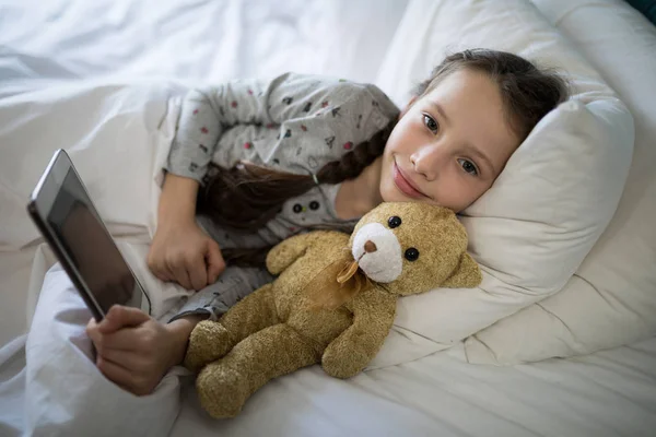 Fille à l'aide de la tablette tout couché sur le lit — Photo