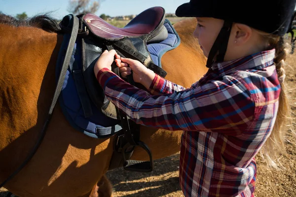 Chica ajustando silla de montar a caballo — Foto de Stock