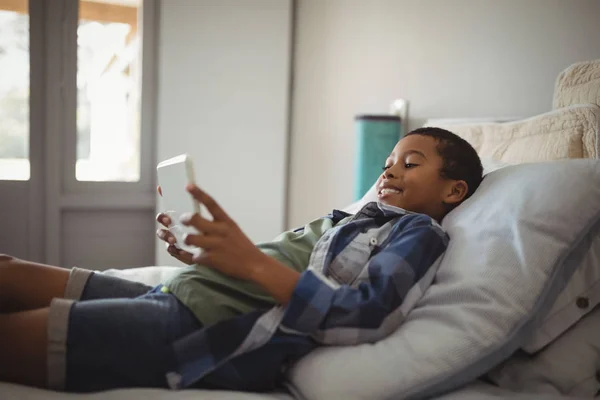 Garçon utilisant la tablette tout en étant couché sur le lit — Photo