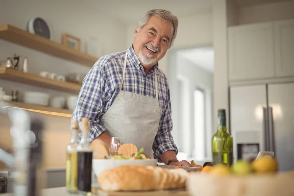 Uomo anziano tagliare le verdure a casa — Foto Stock