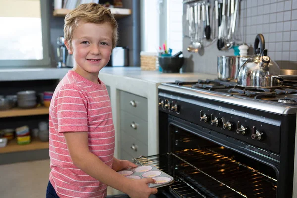 Jongen holding muffin tin in keuken — Stockfoto