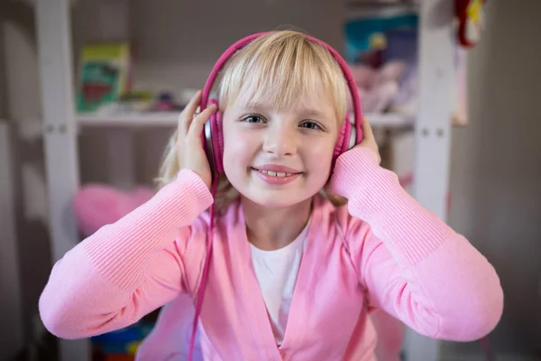 Linda chica escuchando auriculares rosados —  Fotos de Stock