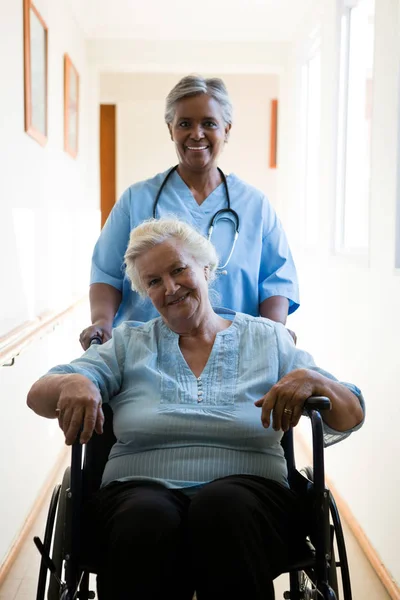 Sjuksköterska driftigt patienten sitter i rullstol — Stockfoto