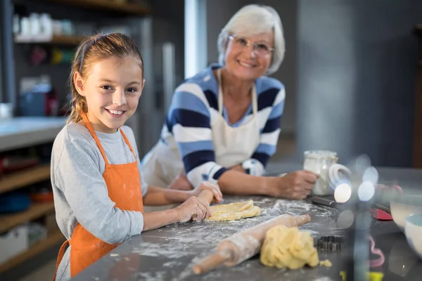 Grandmother and granddaughter flattening dough — Stock Photo, Image
