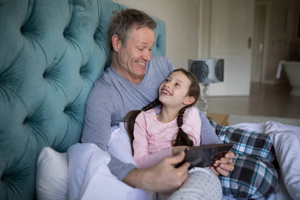 Отец и дочь с помощью планшета на кровати — стоковое фото
