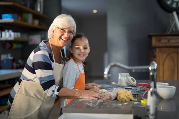 Grandmother and granddaughter flattening dough — Stock Photo, Image