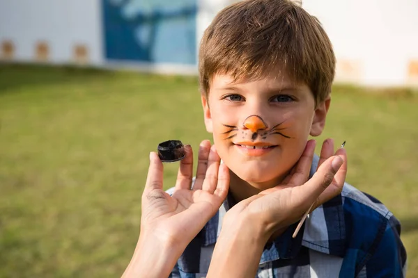 Mano di madre facendo faccia dipingere su ragazzo — Foto Stock