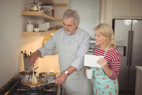 Пожилая пара готовит еду на кухне — стоковое фото