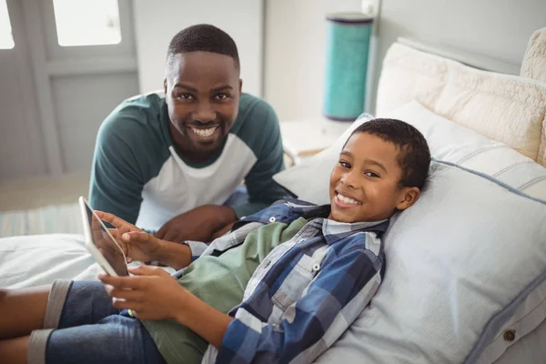 Vader en zoon met tablet in slaapkamer — Stockfoto