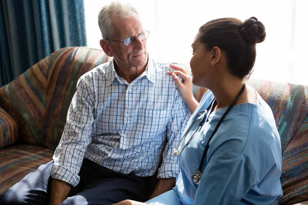 Kvinnliga läkare tröstar senior mannen på soffa — Stockfoto