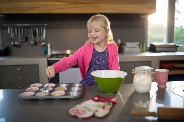 Smiling girl pouring cupcake batter — Stock Photo, Image