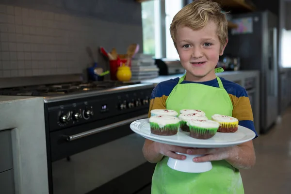 Boy holding plate with cupcakes — Stock Photo, Image