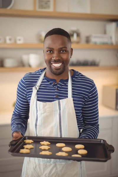 Homme tenant plateau de biscuits dans la cuisine — Photo