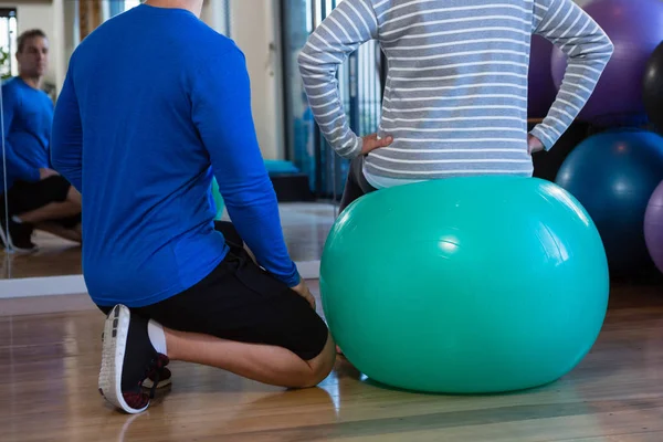 Fysiotherapeut helpen senior vrouw op oefening bal — Stockfoto