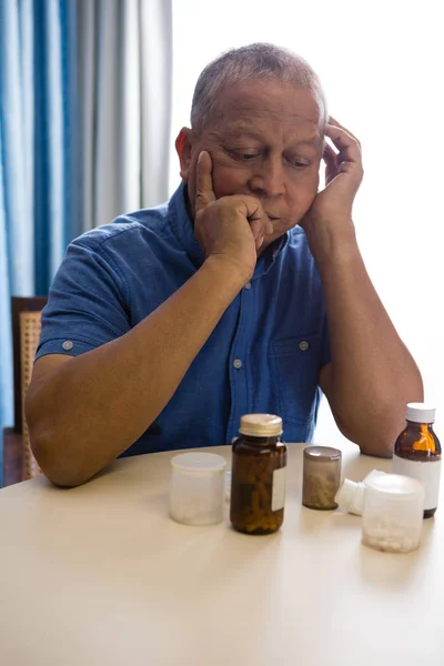 Pensativo hombre mayor mirando las medicinas —  Fotos de Stock