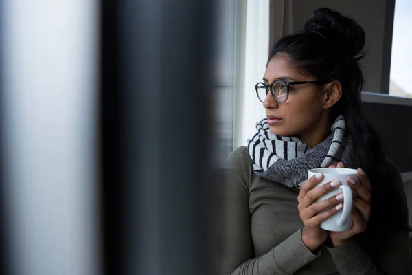 Jeune femme avec tasse de café par fenêtre — Photo