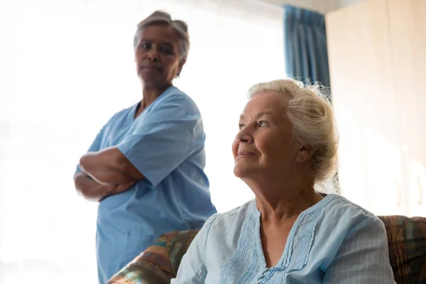 Медсестра смотрит на заботливого пациента на диване — стоковое фото