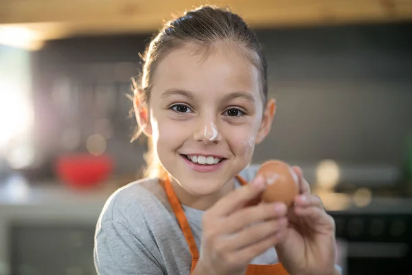 Menina segurando ovos com farinha no nariz — Fotografia de Stock