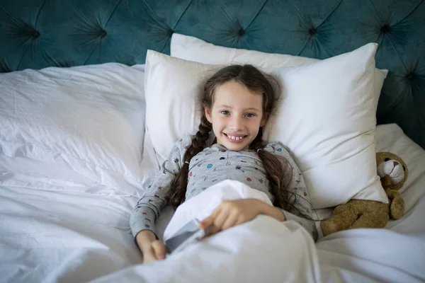 Meisje liggend op bed met teddy beer in slaapkamer — Stockfoto