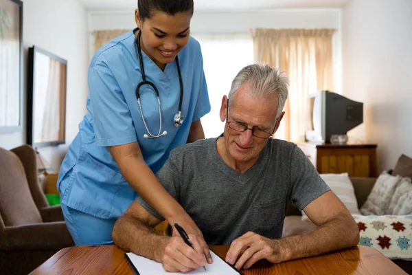 Lekarz pomoc starszy człowiek na piśmie — Zdjęcie stockowe
