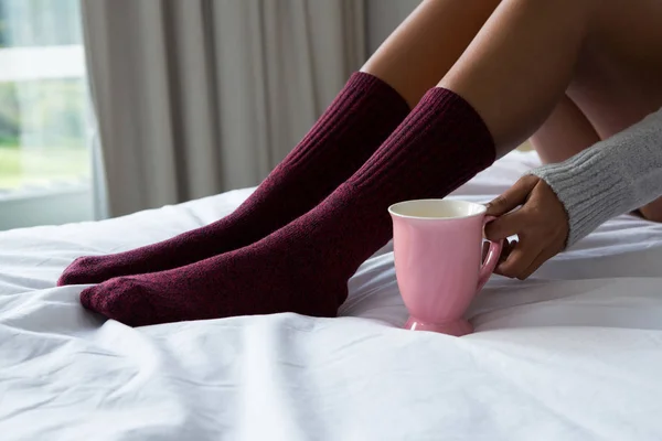 Mulher segurando xícara de café na cama — Fotografia de Stock