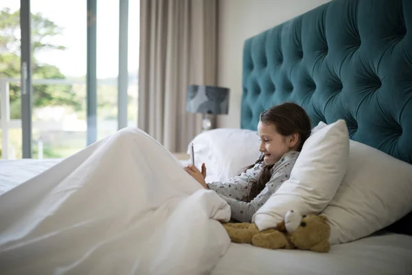 Menina usando telefone na cama no quarto — Fotografia de Stock