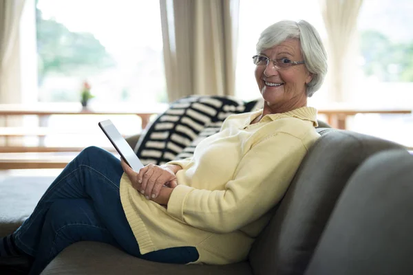 Äldre kvinna med tablett på soffa — Stockfoto