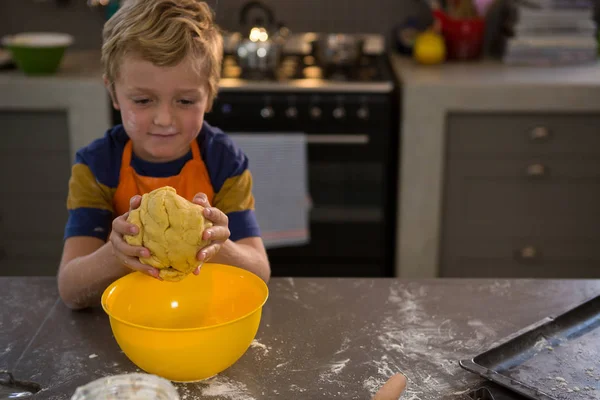 Boy kneading dough over yellow bowl — Stock Photo, Image